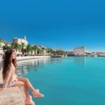 Waterfront of Split, Croatia. Young female traveler with pink backpack enjoying the seafront. Woman looking at view Diocletian palace on famous travel destination