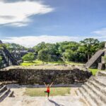 young female traveler doing morning yoga at tikal temples in guatemala