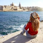 young traveler woman looks out over water to the city of valletta in malta