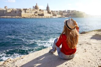 young traveler woman looks out over water to the city of valletta in malta