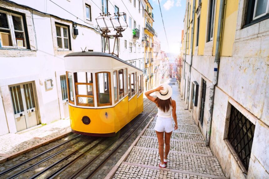 Woman tourist walking in narrow streets of Lisbon city old town. Famous retro yellow funicular tram on a sunny summer day. Tourist attraction.