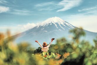 Happy tourist traveler woman enjoying with open arms on lake kawaguchiko with mount fuji in japan, spring and summer, Japan travel vacation