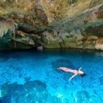 solo traveler swimming in tulum cenote