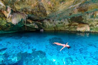 solo traveler swimming in tulum cenote
