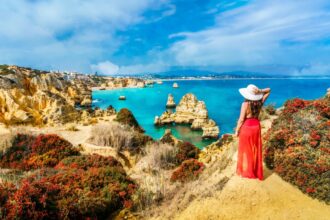 Woman in a red dress looking at the sea in the Algarve, Portugal