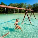 Woman in lake Bacalar on a swing