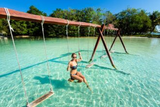 Woman in lake Bacalar on a swing