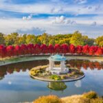 Red foliage lining reflective pond in Forest Park of St. Louis