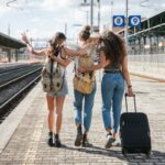 3 friends with luggage at train station