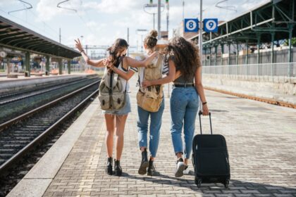 3 friends with luggage at train station