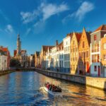 Tourist boat on canal Spiegelrei and Jan Van Eyck Square in the morning in Bruges, Belgium