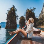 Happy solo traveler asian woman with hat relax and sightseeing on Thai longtail boat