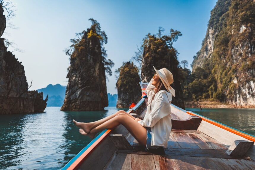 Happy solo traveler asian woman with hat relax and sightseeing on Thai longtail boat