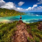 Hiker standing majestically on top of a cliff on the Pu