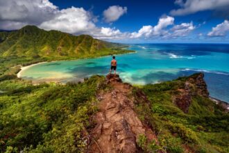 Hiker standing majestically on top of a cliff on the Pu