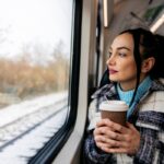 Woman with coffee riding train through snow