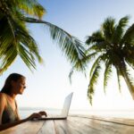 Digital nomad working outdoors under palm trees