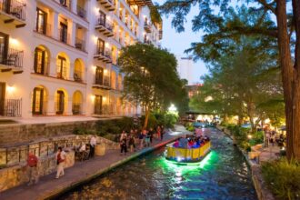 Boat ride through San Antonio River Walk in evening