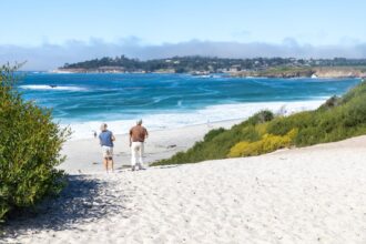 Couple walking on white sand beach in Carmel, CA