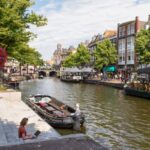 Woman on laptop near canal in Netherlands