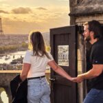 Man and woman walking out onto Parapet of a tower in Paris with the Eiffel Tower in the Background