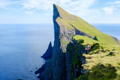 Adventure seekers stand atop stunning Mylingur cliffs in the Faroe Islands, capturing the majestic beauty of the rugged landscape.