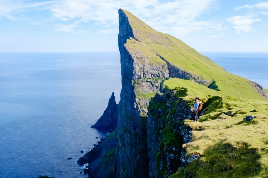 Adventure seekers stand atop stunning Mylingur cliffs in the Faroe Islands, capturing the majestic beauty of the rugged landscape.