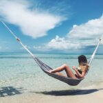 Tourist relaxing on beach hammcok in Eleuthera, Bahamas