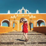 Young Woman Admiring The Colonial Architecture Of Izamal, Mexico