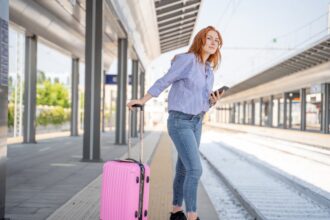 Woman with pink luggage waiting for train