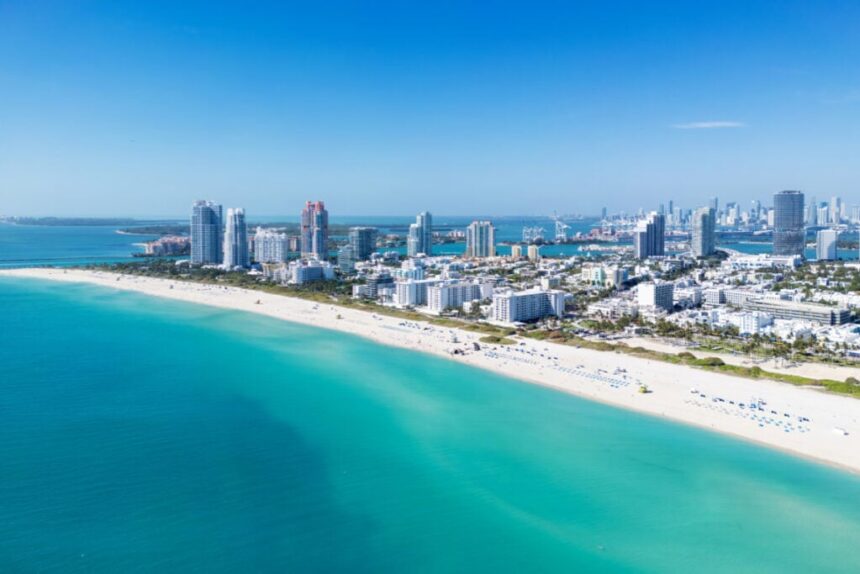 Miami Beach on blue sky. Skyline aerial view. Miami city. Tropical Miami scene. Miami district sky view. Famous oceanfront. Panoramic coastline. South beach panorama view. Summer holiday vibes.