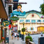 People enjoy a warm summer evening on the street in Leavenworth city center among Bavarian-style buildings and businesses
