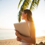 Woman holding laptop on tropical beach