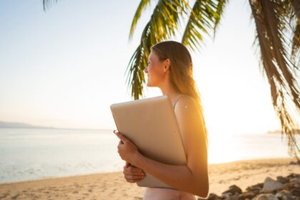 Woman holding laptop on tropical beach