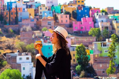 Colorful houses in Guanajuato, Mexico with woman drinking from a mug