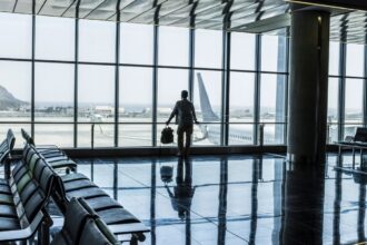 One man standing at the airport gate waiting his flight with delay or canceled