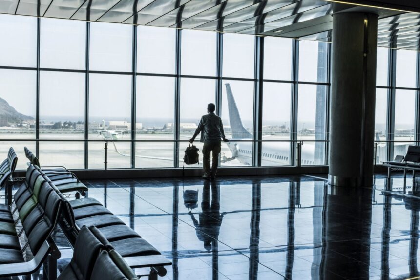 One man standing at the airport gate waiting his flight with delay or canceled