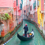 Gondalier guiding tourists through Venice canal